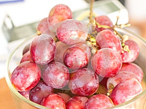 Red grapes have white stains in the glass bowl.