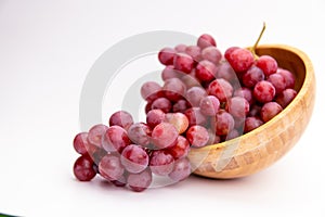 Red grapes in a woodenn bowl isolated on white background. Fresh bunch of fruits. Selective focus photo