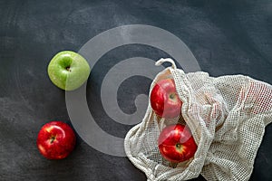 Red and green apples in cotton mesh eco bag on a dark background