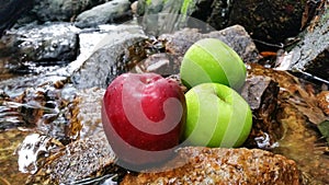 Red green apples in natural waterfall and stone blackground