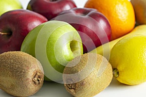 Red green apples with ripe bananas and kiwi orange lemon on a white background