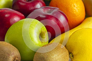 Red green apples with ripe bananas and kiwi orange lemon on a white background