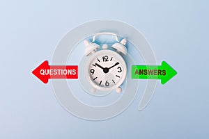 Red and green arrows with text questions vs answers. Concept of choice. Two Arrows and White alarm clock on blue background, top