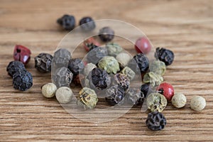 Red, green and black peppercorns on wood