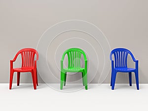 Red, green and blue generic plastic chairs against a wall