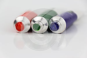 Red, green, blue paint tubes on white background
