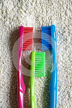 Red, green and blue toothbrush lying on a towel.