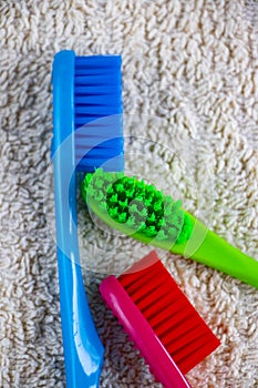 Red, green and blue toothbrush lying on a towel.