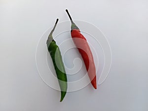 A red and a green chilli pepper on a white background