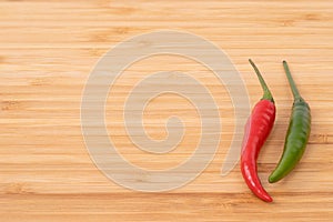 Red and green chilli pepper on wood chopping board.