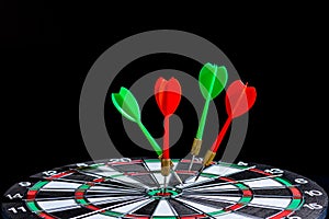 Red and green dart arrow hitting target center is Dart board Isolated on black background