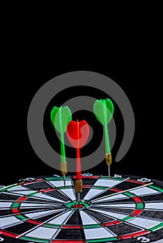 Red and green dart arrow hitting target center is Dart board Isolated on black background