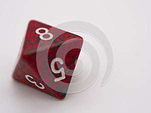 Red and green eight-sided die displaying a 8