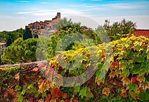 Red and green grape leaves and panoramic view of Saint-Paul-de-Vence town in Provence, France