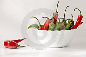 Red and green hot chili pepper in a ceramic bowl