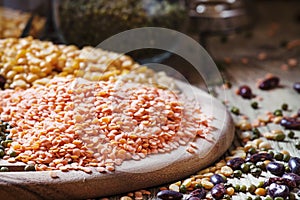 Red and green lentils and beans and peas, dark wood background,