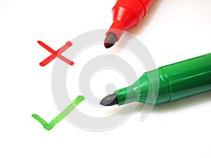 Red and green marker pens with cross and checklist sign