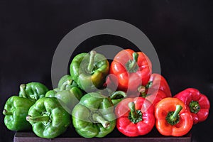 Red and green raw peppers on a black background