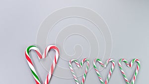 Red, green and white candy canes in the shape of heart on grey background. Valentine\'s Day concept.
