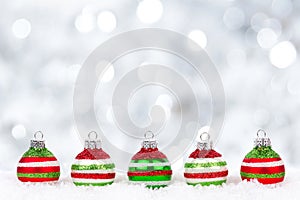 Red, green, white Christmas ornaments in snow with twinkling background photo