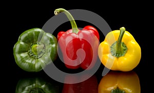 Red,green,yellow bell peppers isolated on black