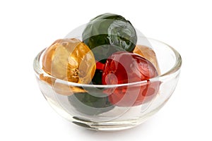 Red, green and yellow glace cherries in glass bowl isolated on w