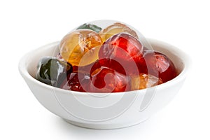 Red, green and yellow glace cherries in white bowl isolated on w