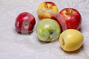 Red green and yellow healthy apples sitting on wrinkled paper.