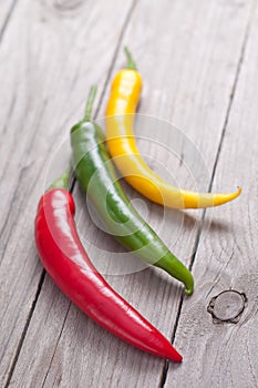 Red, green and yellow hot chili pepper on wooden planks.