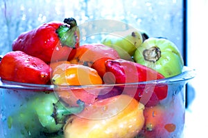 Red , green and yellow peppers in a transparent bowl