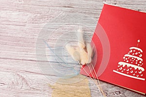 Red greeting card and dried flowers on a light wooden background