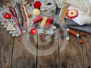 Red and grey accessories for needlework on wooden background. Knitting, embroidery, sewing. Small business. Income from hobby.