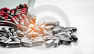 Red and grey capsule pills on stainless steel drug tray and gray capsules on white background. Migraine prophylaxis treatment