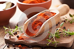 Red ground paprika spice in wooden scoop, bowl