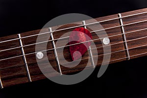 Red guitar pick on the fingerboard