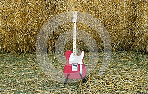 Red guitar telecaster on a straw stack background in a summer day