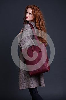 Red hair fashion model holding large leather bag