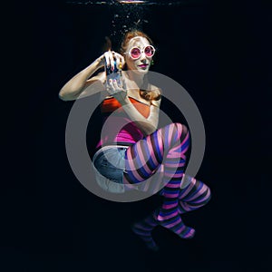 Red hair funny girl on the dark background underwater