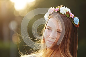 Red hair Girl Portrait in circlet of flowers on nature green background