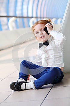 Red hair little cute girl talks by cell phone on