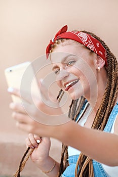 Red hair teenage girl with freckles in casual style doing selfie in summer day