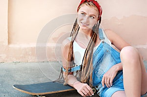 Red hair teenage girl with freckles in casual style with skateboard in summer day on the street