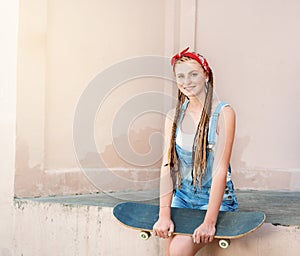 Red hair teenage girl with freckles in casual style with skateboard in summer day on the street