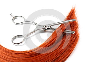 Red hair and thinning scissors on white background.