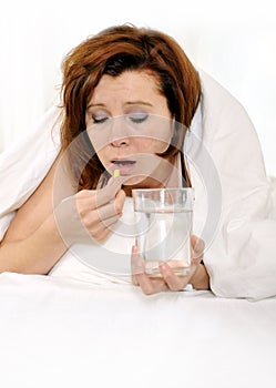 Red hair woman with hangover taking headache pill