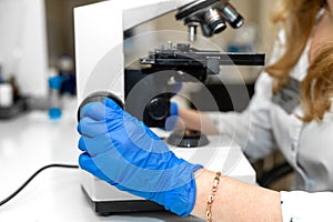 Red hair woman lab technician looking through microscope analyse blood