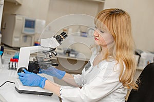 Red hair woman lab technician looking through microscope analyse blood