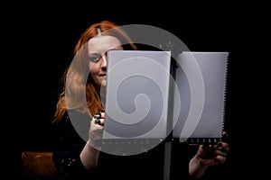 Red hair woman painting. Portrait of an artist against black background