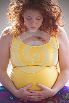 Red hair young pregnant woman hold her belly indoor shot