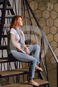 Red-haired attractive woman sits on a metal staircase